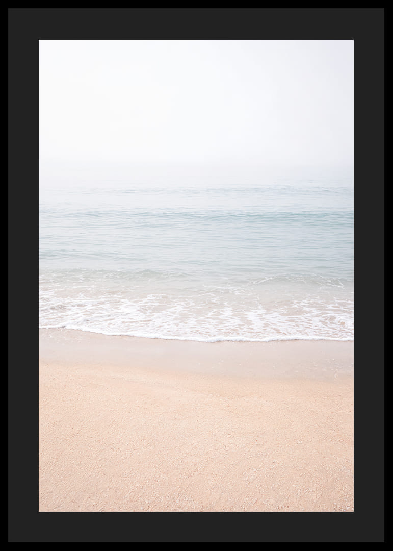 A misty coast where the sea meets the sand in soft tones.-12