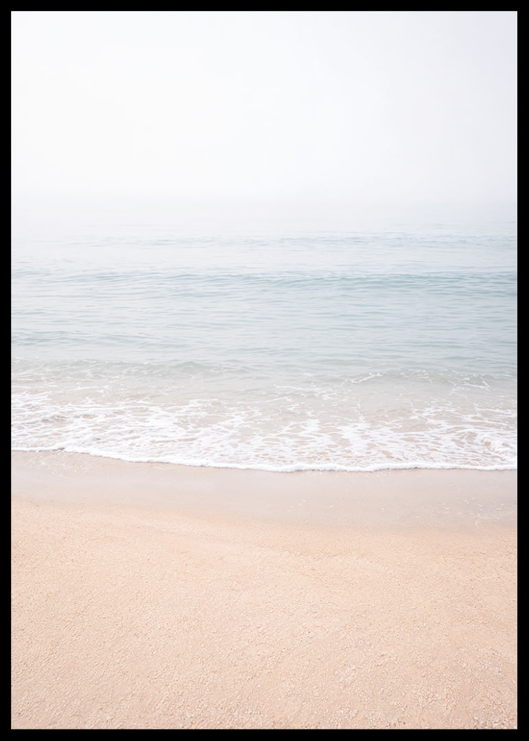 A misty coast where the sea meets the sand in soft tones.-12