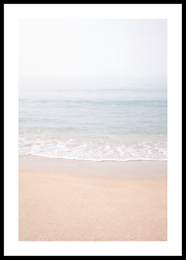 A misty coast where the sea meets the sand in soft tones.-12
