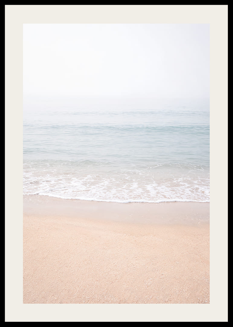 A misty coast where the sea meets the sand in soft tones.-12