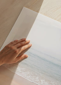 A misty coast where the sea meets the sand in soft tones.-9