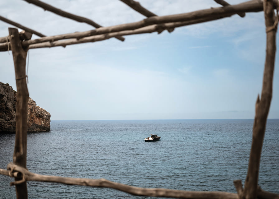 A lone boat rests under a clear blue sky in the arms of the ocean.-12
