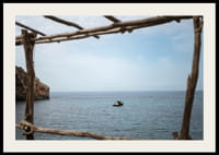 A lone boat rests under a clear blue sky in the arms of the ocean.-2