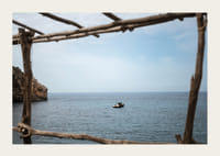 A lone boat rests under a clear blue sky in the arms of the ocean.-3
