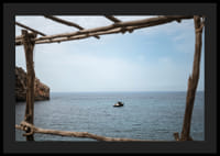 A lone boat rests under a clear blue sky in the arms of the ocean.-4