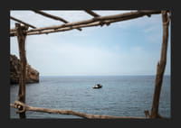 A lone boat rests under a clear blue sky in the arms of the ocean.-5