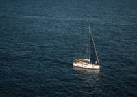 En segelbåt glider över det stilla, djupblå havet.-7
