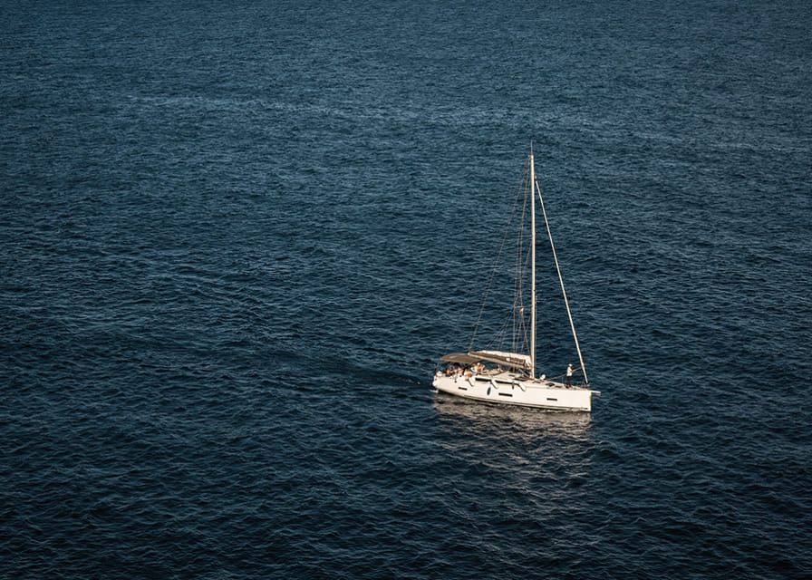 En segelbåt glider över det stilla, djupblå havet.-12