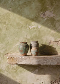 Tre vasi rustici appoggiati a un muro consumato dal tempo.-7