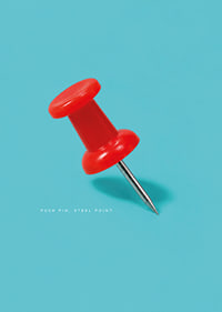 A shiny red pushpin against a turquoise background with a playful graphic feel.-7