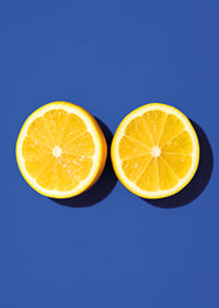 Two sunny yellow lemon halves shine against a deep blue background with fresh energy.-7