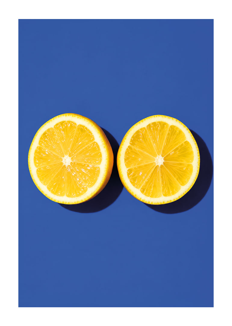 Two sunny yellow lemon halves shine against a deep blue background with fresh energy.-12