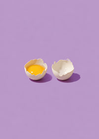 A golden egg in cracked shell against a purple background with a playful, stylish feel.-7