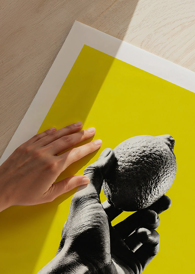 A hand lifts a lemon against an intensely yellow background with graphic energy.-12