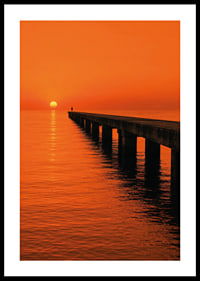 A lone person on a pier in a glowing orange sunset light.-0