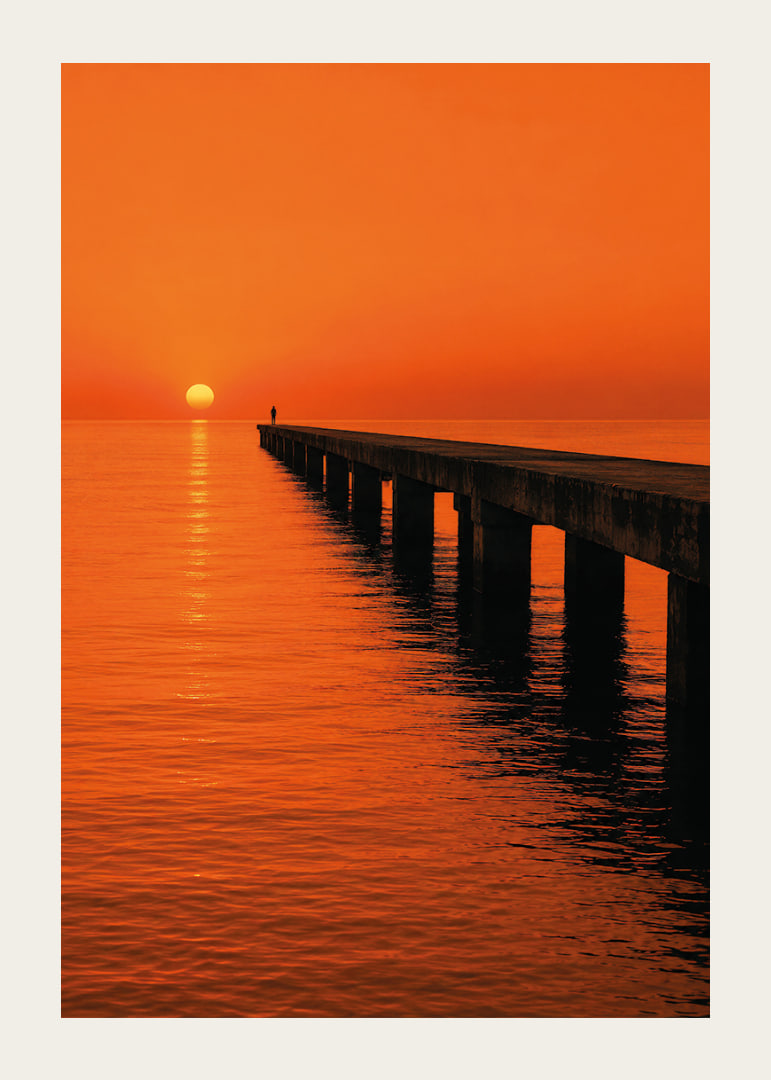 A lone person on a pier in a glowing orange sunset light.-12