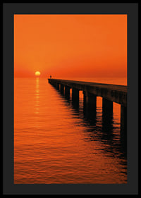 A lone person on a pier in a glowing orange sunset light.-4