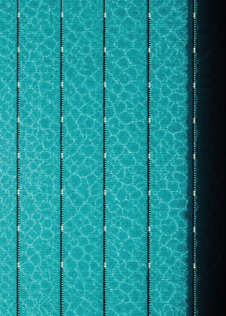 Turquoise pool water and dark track lines create a cool, graphic rhythm.-12