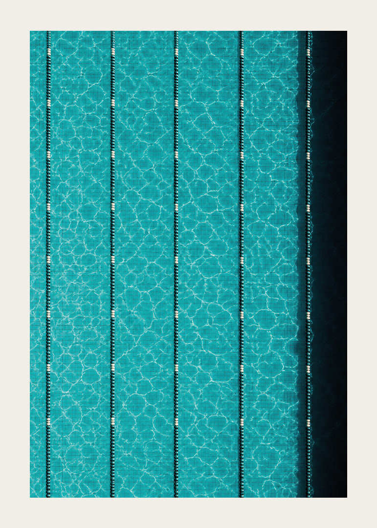 Turquoise pool water and dark track lines create a cool, graphic rhythm.-12