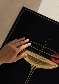 Una copa de cóctel dorada con burbujas y labios rojos sobre un fondo negro intenso.-3