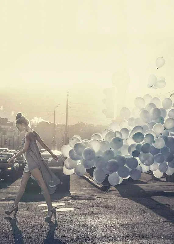 Photograph of woman in gray dress with blue balloons on street-12