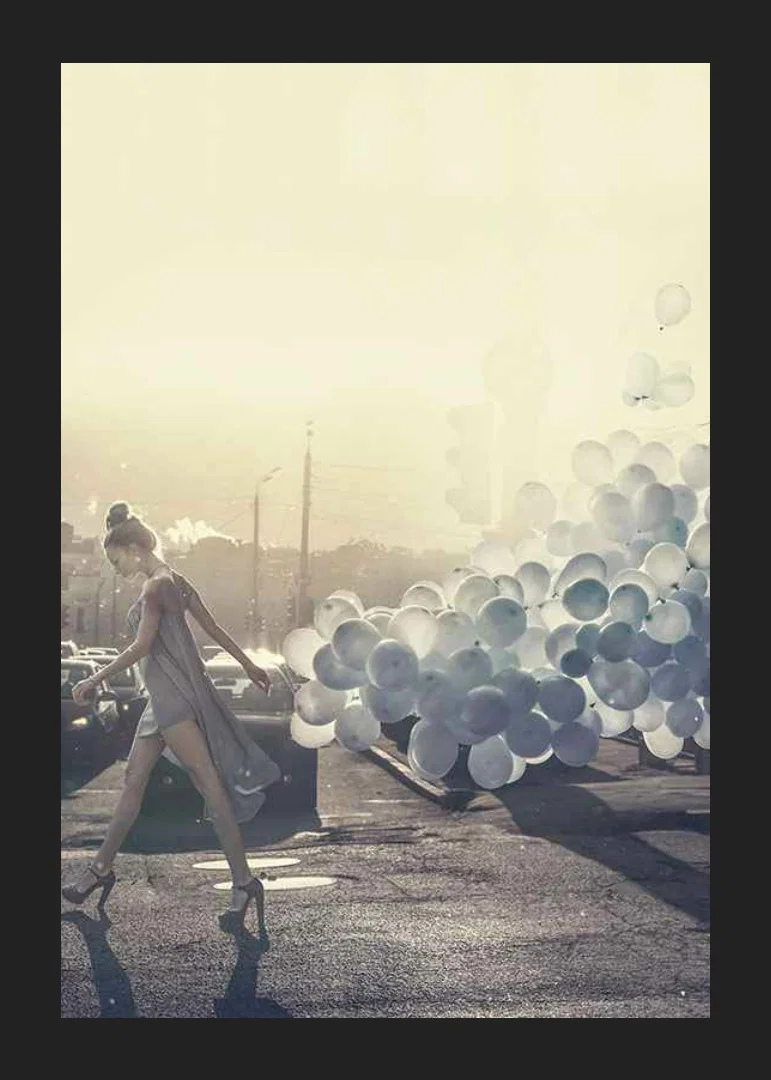 Photograph of woman in gray dress with blue balloons on street-12