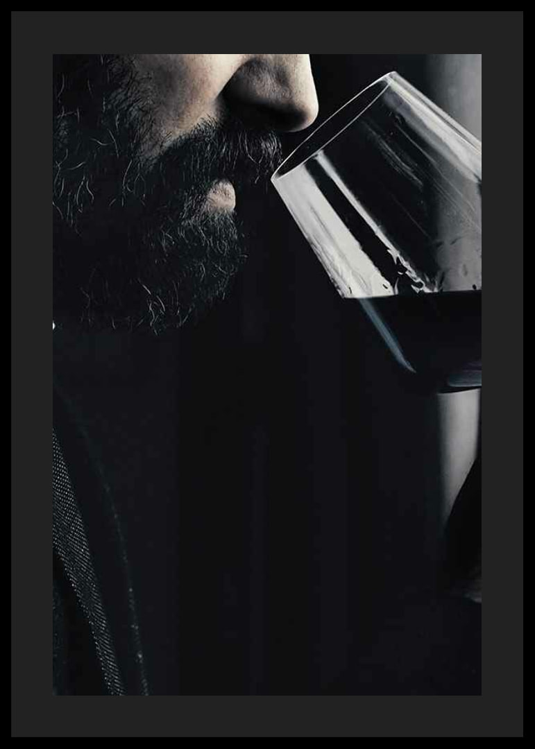 Close-up of man with beard smelling red wine in glass-12