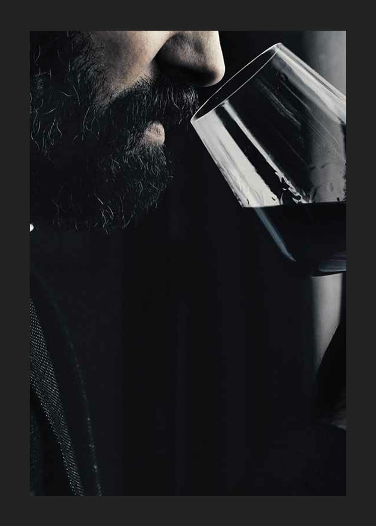 Close-up of man with beard smelling red wine in glass-12