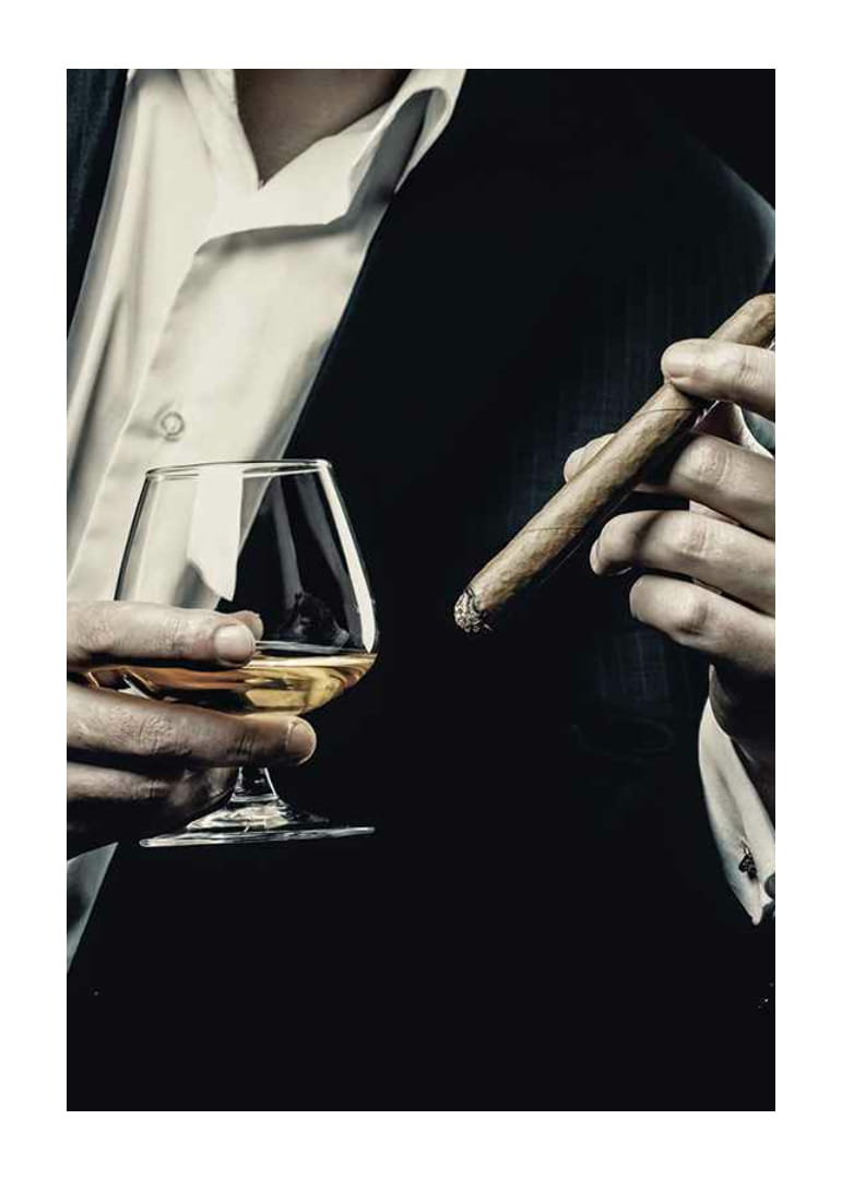 Primer plano de un hombre de traje con copa de coñac y cigarro-12