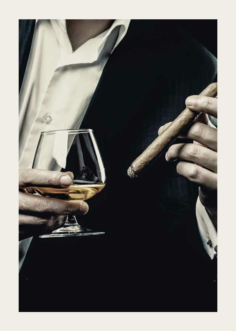 Primer plano de un hombre de traje con copa de coñac y cigarro-12