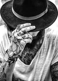 Black and white close-up of tattooed man with hat and jewelry-7