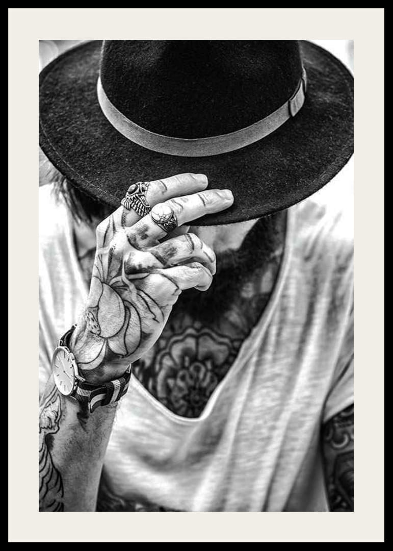 Svartvit närbild av tatuerad man med hatt och smycken-12