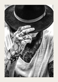 Svartvit närbild av tatuerad man med hatt och smycken-3