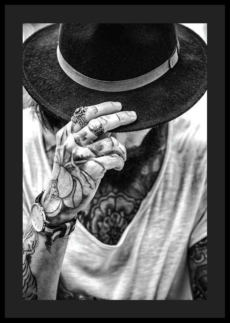 Svartvit närbild av tatuerad man med hatt och smycken-12
