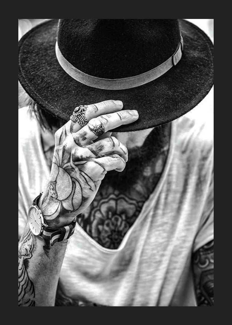 Black and white close-up of tattooed man with hat and jewelry-12