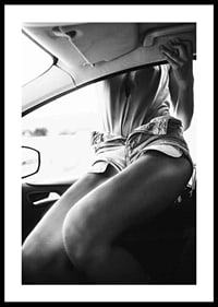 Black and white photo of woman in shorts, sitting in car window-0
