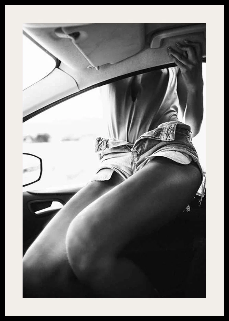 Black and white photo of woman in shorts, sitting in car window-12