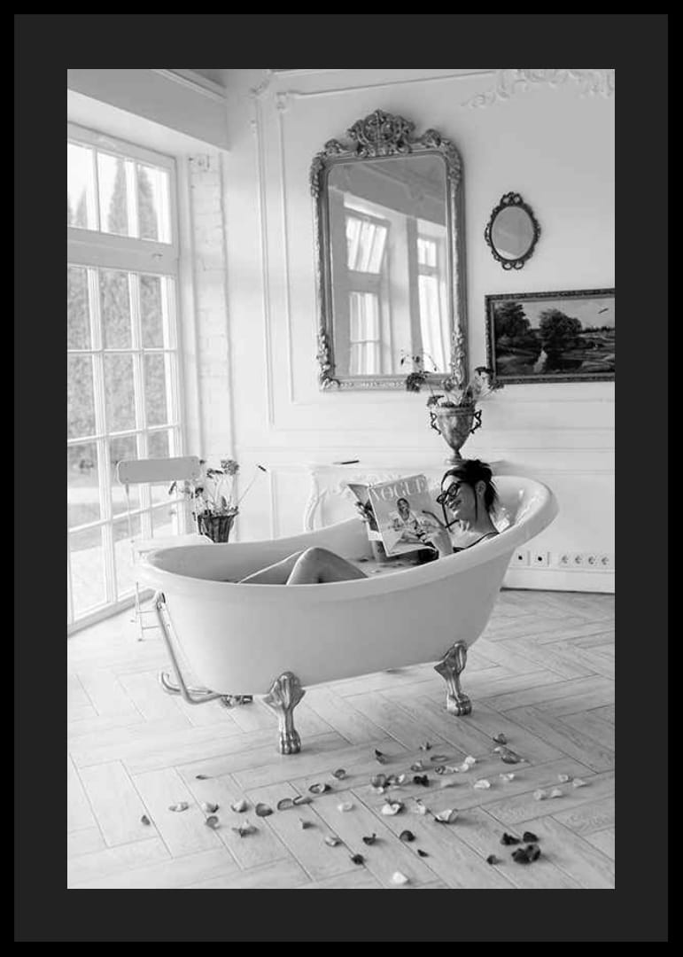 Svartvitt fotografi av kvinna i badkar som läser tidning-12