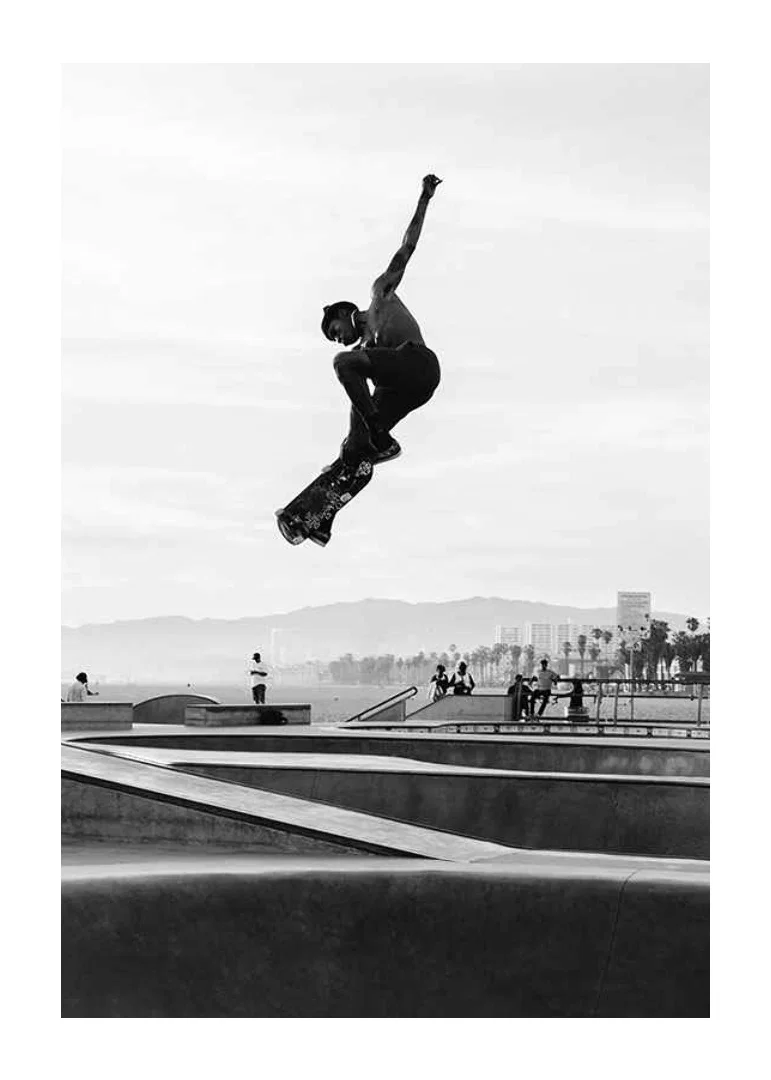 Black and white photograph of skateboarder in the air over skatepark-12