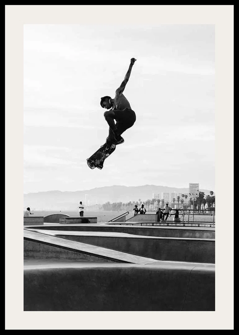 Black and white photograph of skateboarder in the air over skatepark-12