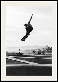 Mustavalkoinen valokuva skeittaajasta ilmassa skeittipuiston yllä-2