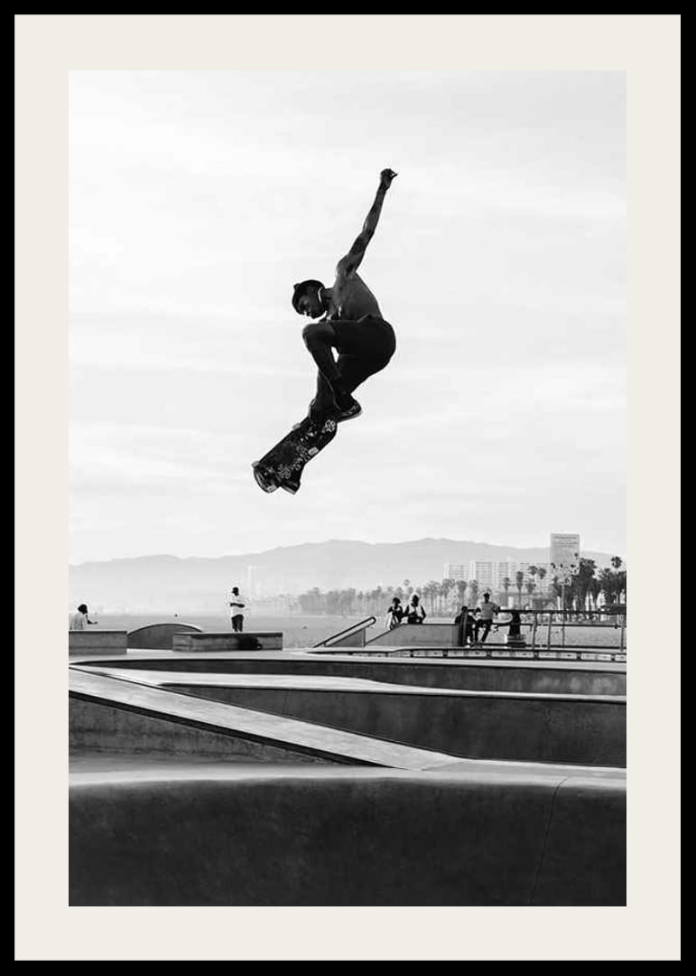 Mustavalkoinen valokuva skeittaajasta ilmassa skeittipuiston yllä-12