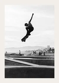 Black and white photograph of skateboarder in the air over skatepark-3