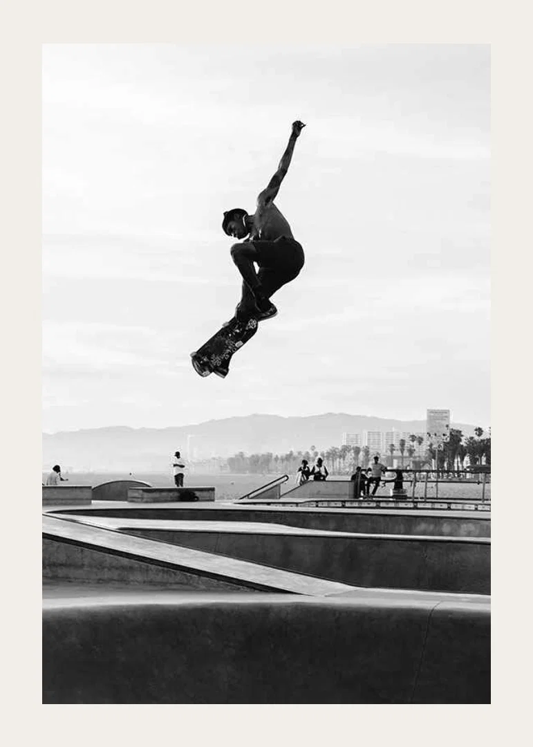 Black and white photograph of skateboarder in the air over skatepark-12