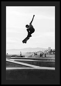 Black and white photograph of skateboarder in the air over skatepark-4