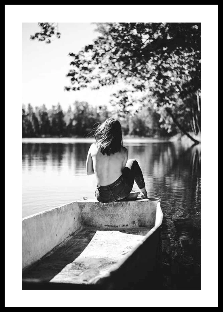 Black and white photograph of woman in boat on calm lake with trees-12
