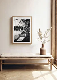 Black and white photograph of woman in boat on calm lake with trees-8