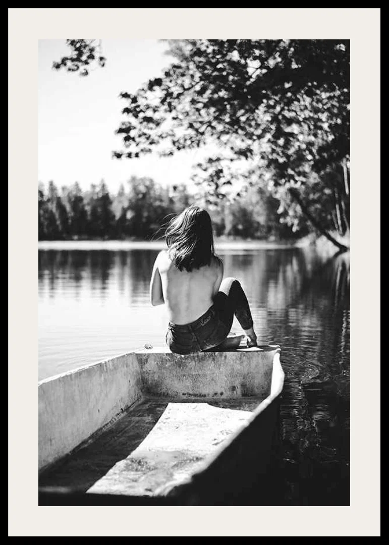 Black and white photograph of woman in boat on calm lake with trees-12