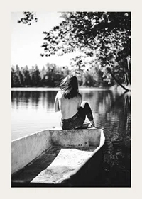 Black and white photograph of woman in boat on calm lake with trees-3
