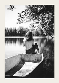 Fotografía en blanco y negro de una mujer en un bote en un lago tranquilo con árboles.-3
